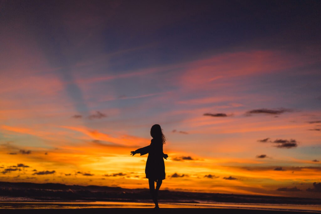 people on the beach at sunset. the girl is jumping against the b